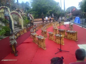 Fifty gender wayang set up on an empty outdoor stage, gold contrasting against the red carpeted ground."