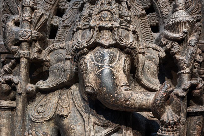 Ganesha, the elephant-headed god, is depicted seated with four arms, holding various objects.