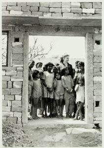 A woman and children behind a doorway of a stone building