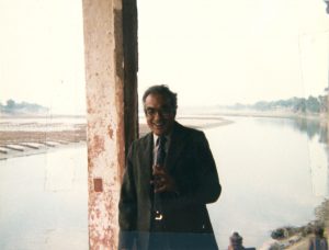 a man leaning against a post with a river in the background