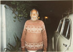 a photograph of a man standing next to a car