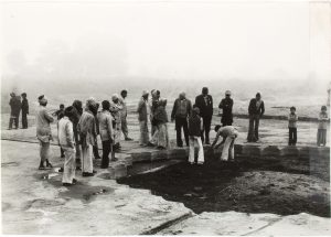 photograph of a group of villagers standing next to a scalloped shape pool