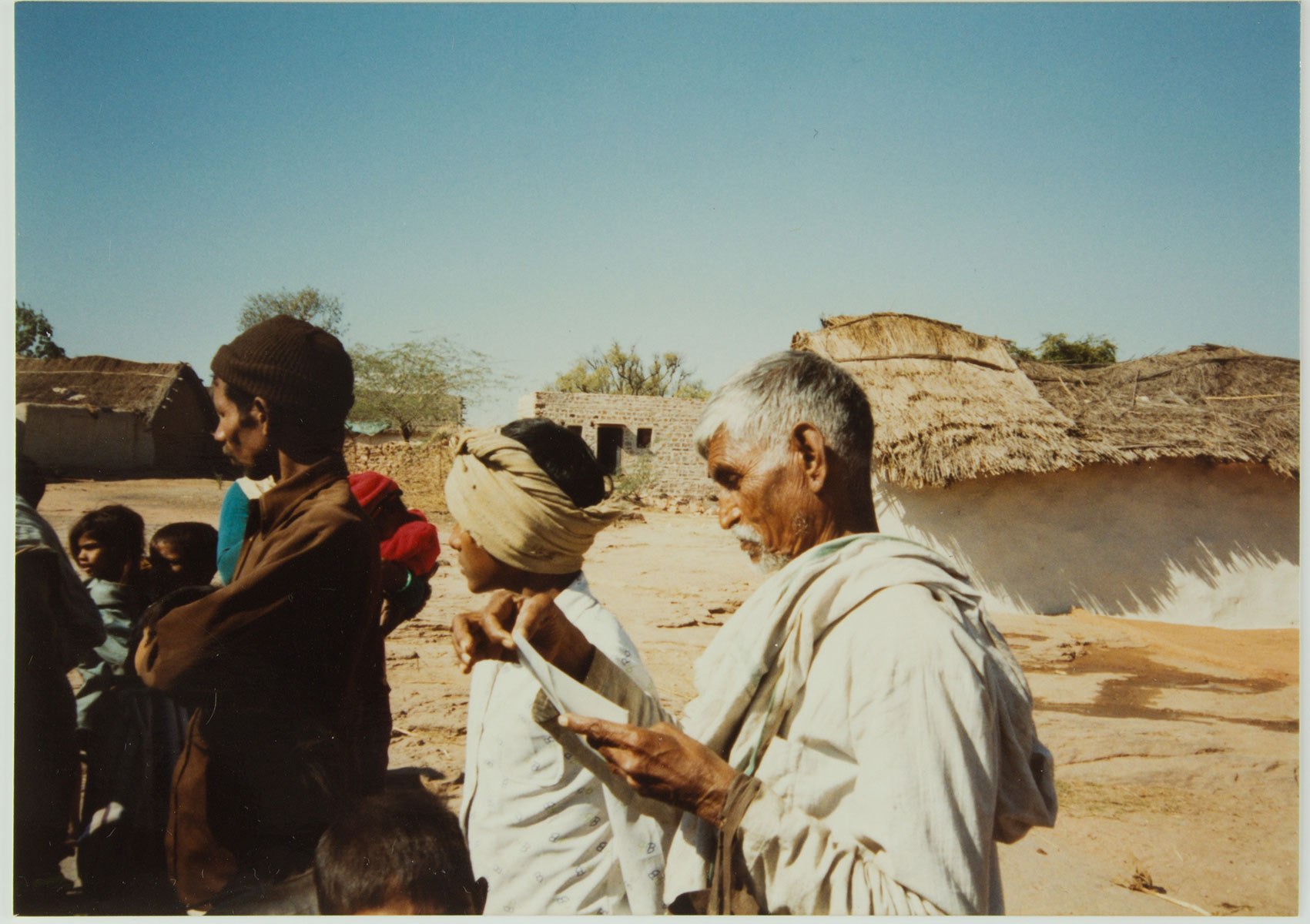 photograph of a group of people and a man reading a slip of paper