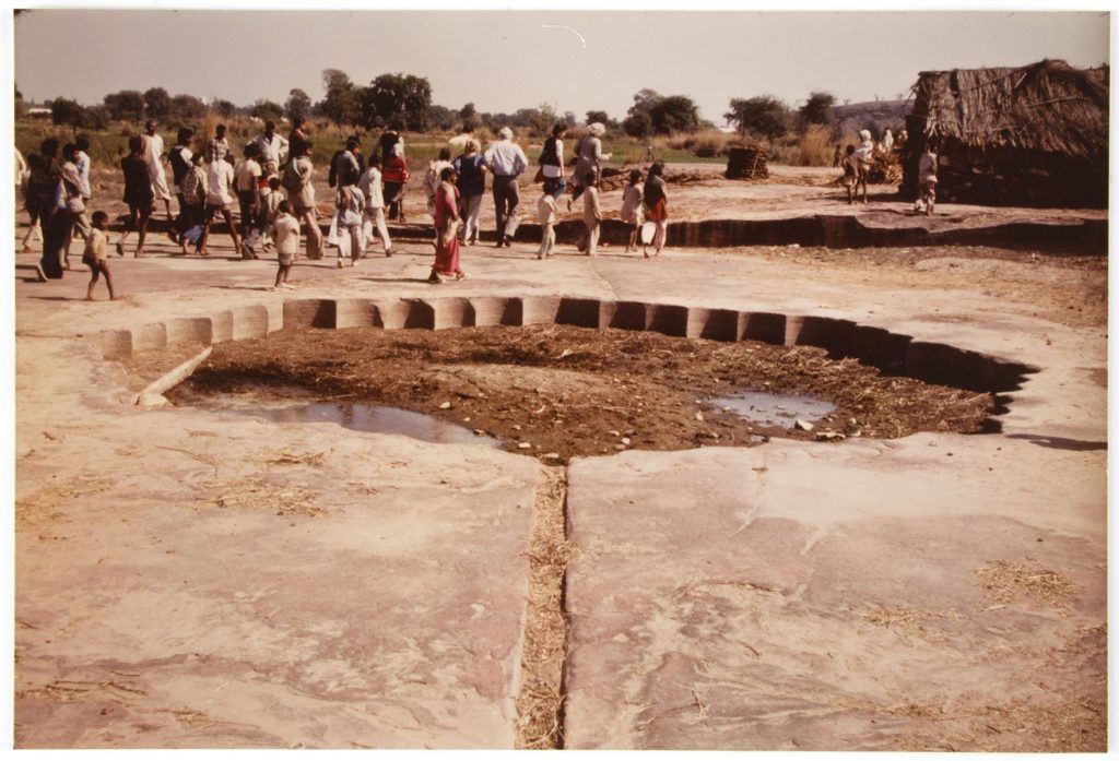 photograph of aa large pool of water with a group of people walking past.