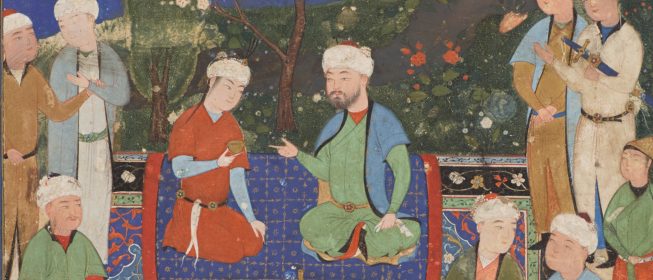 two men kneeling on a rug in a garden surrounded by other men