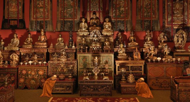Bronze statues gleam in warm, dim lighting in the Tibetan Buddhist Shrine Room.