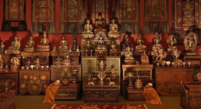 Bronze statues gleam in warm, dim lighting in the Tibetan Buddhist Shrine Room.
