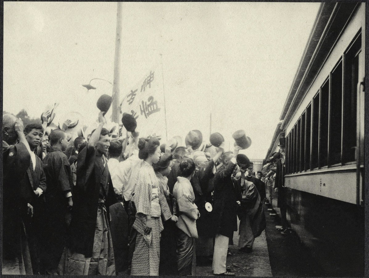 Japanese crowds wave to a train carriage enroute from Yokohama to Tokyo