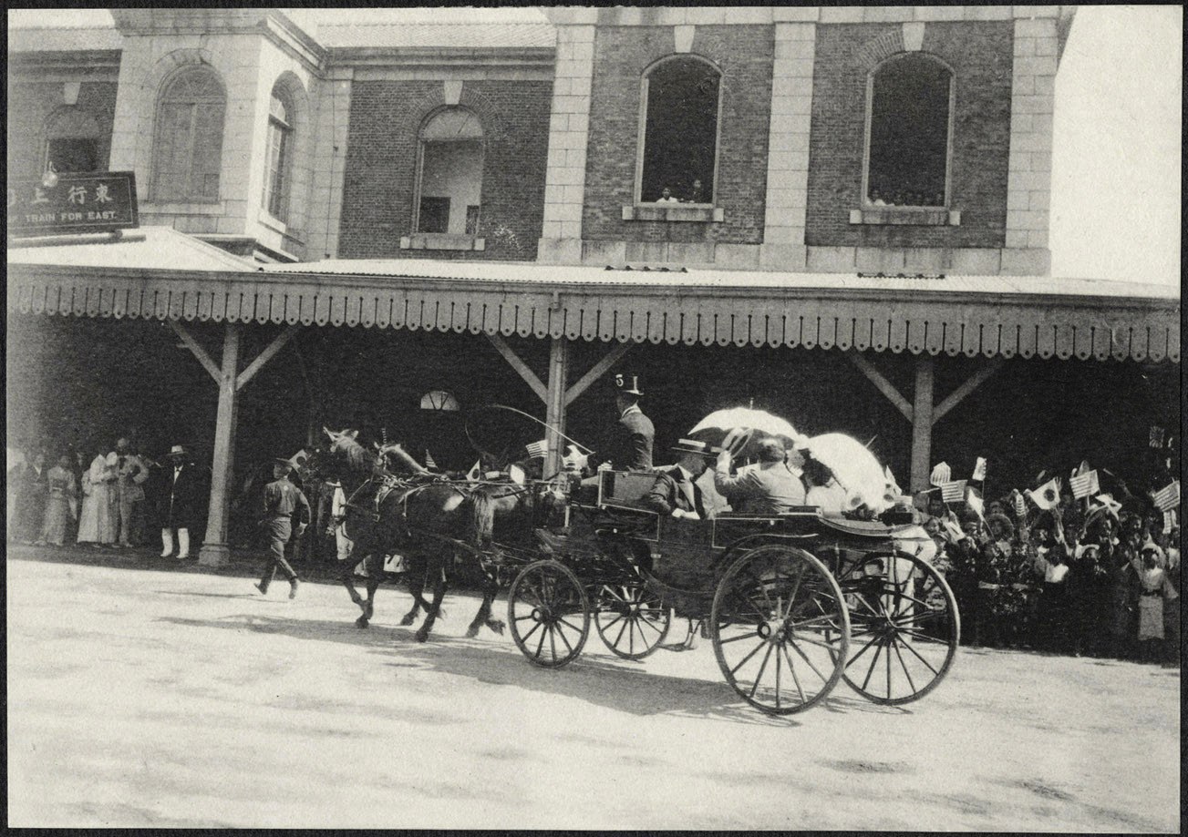 Carriage with William H. Taft and Alice Roosevelt cheered by flag-waving crowd in front of Kyoto Station