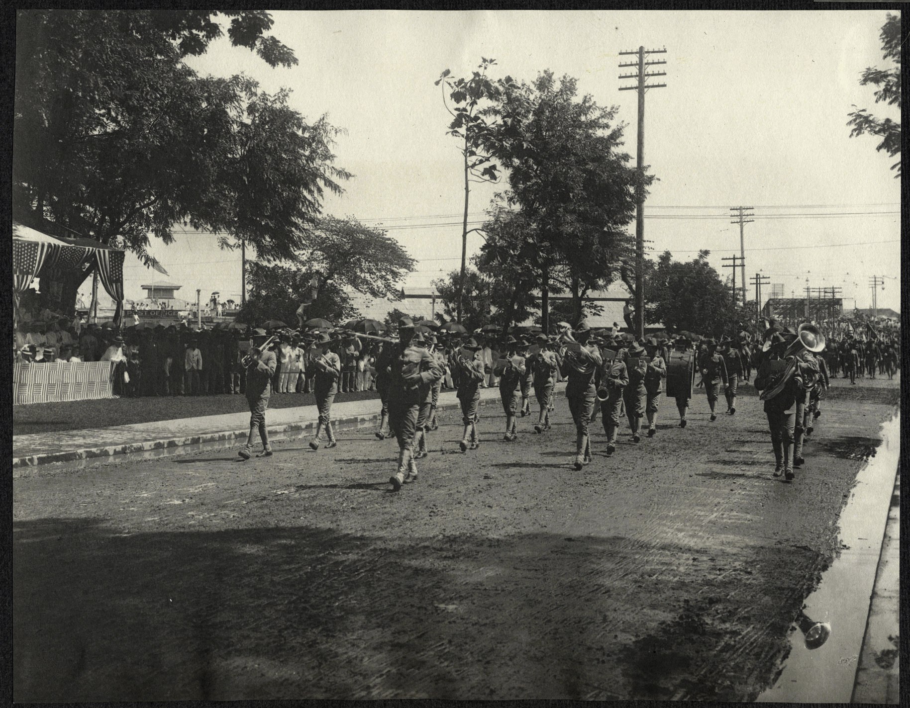 Manila: Group of American soldiers with banner march before viewing stand