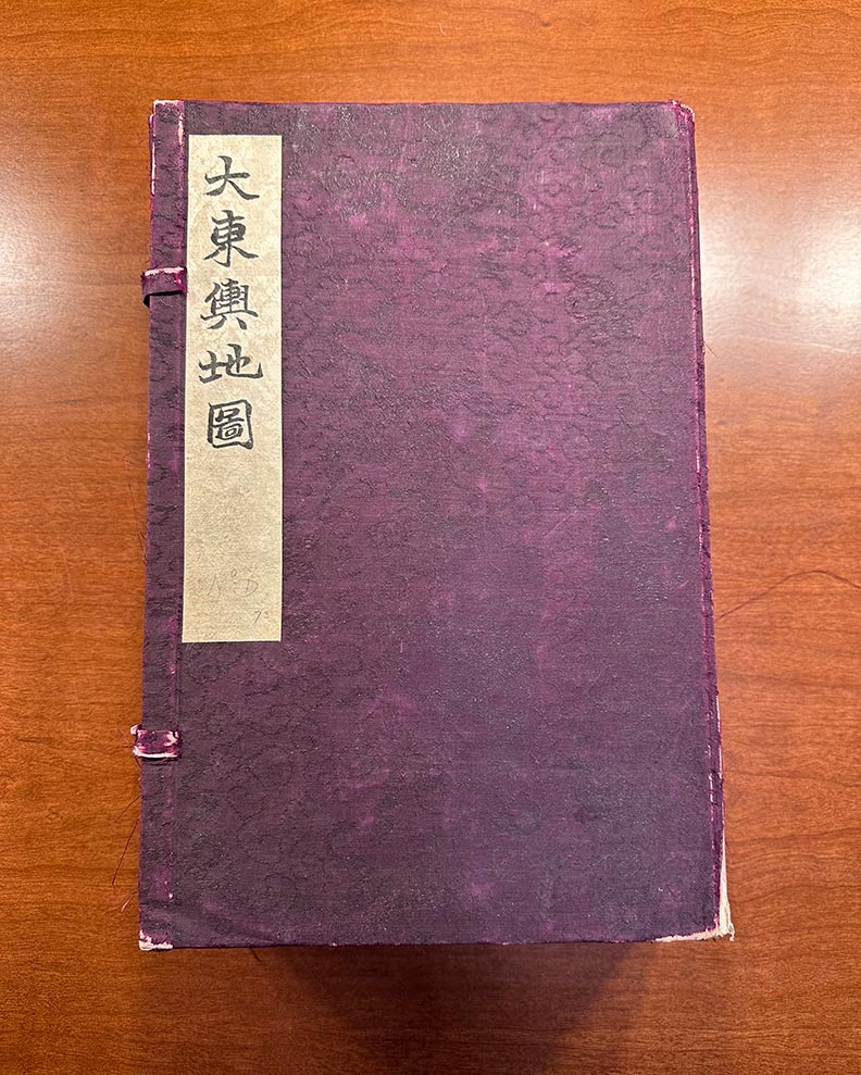 A deep purple cover encloses the map booklets. The map's name in Chinese characters appears on the upper left corner.