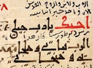 Manuscript page written in red ink that switches to black on the bottom half of the page. The right side of the page is in Arabic, the left in Greek