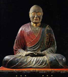 Sculpture of a monk, with some red and dark coloring