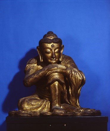 Buddha seated with his chin on his knee