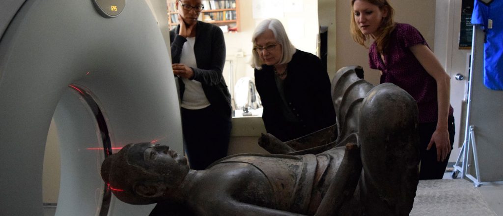 Conservators observe the Freer Buddha statue entering an instrument for CT scanning. 