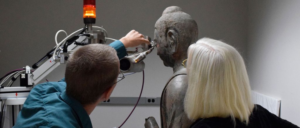 Conservators study the Freer buddha statue. 