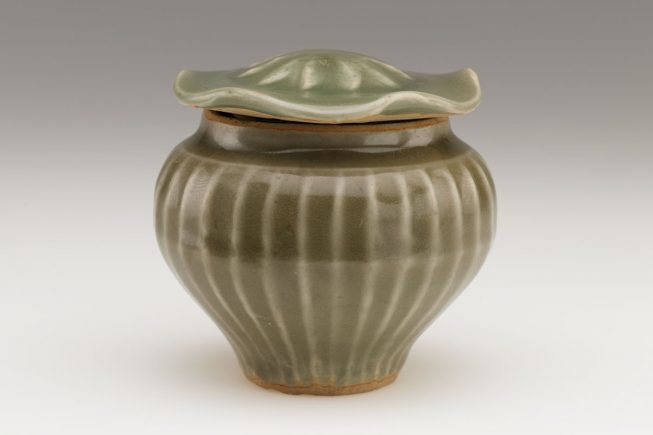 a ceramic pot with a wavy-edged lid and narrow foot