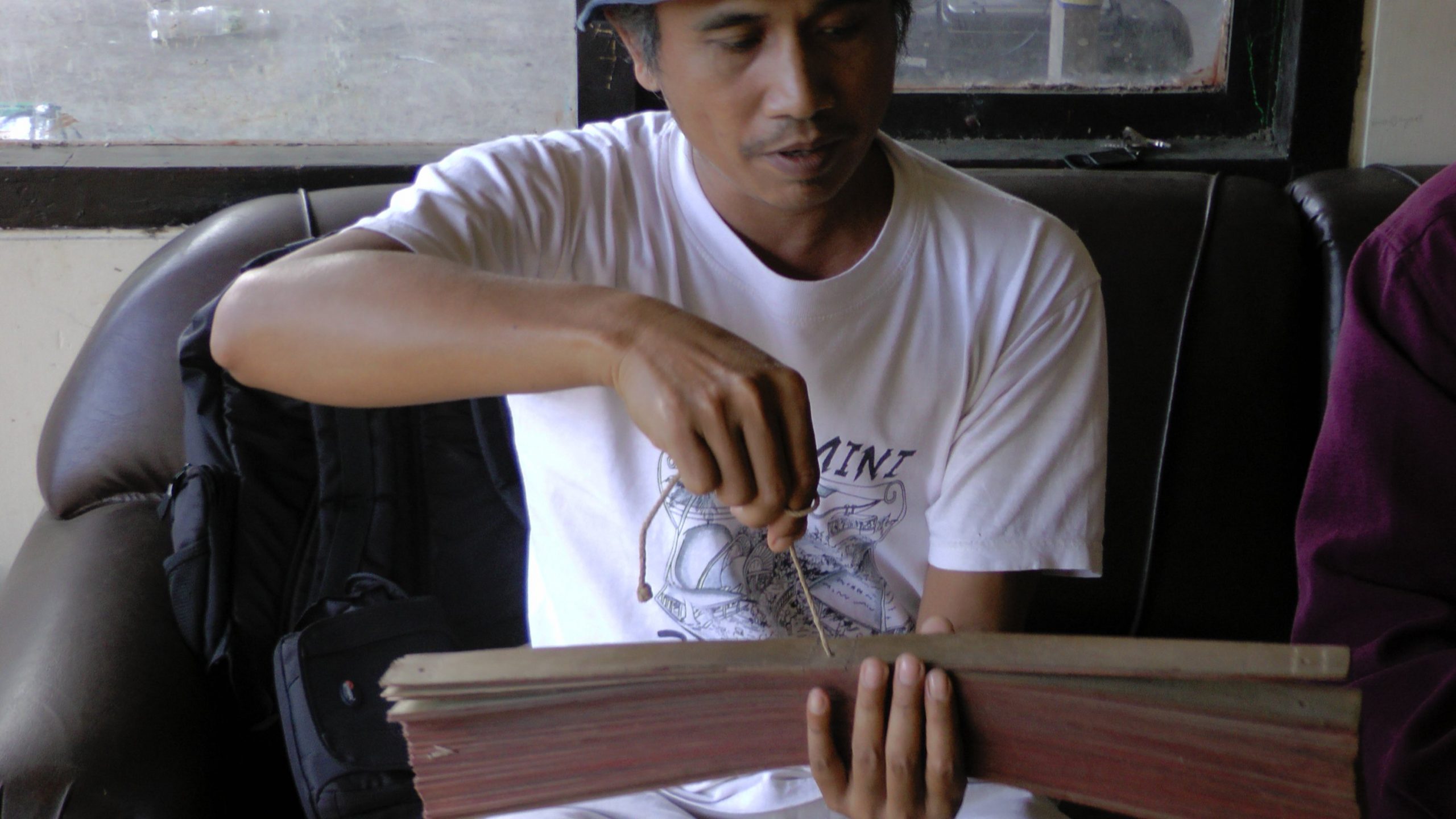 A man holding a lontar manuscript.