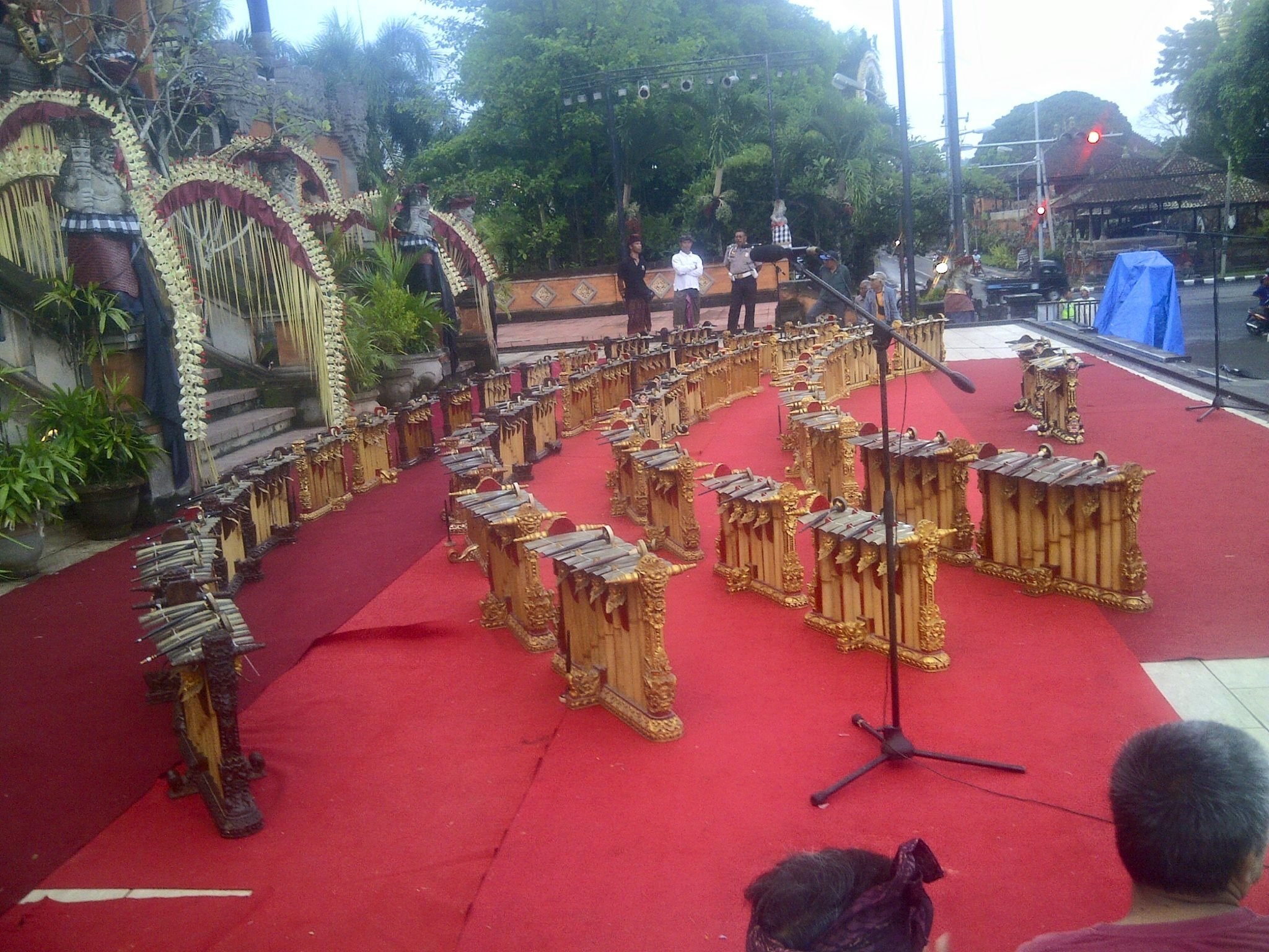 Fifty gender wayang set up on an empty outdoor stage, gold contrasting against the red carpeted ground.