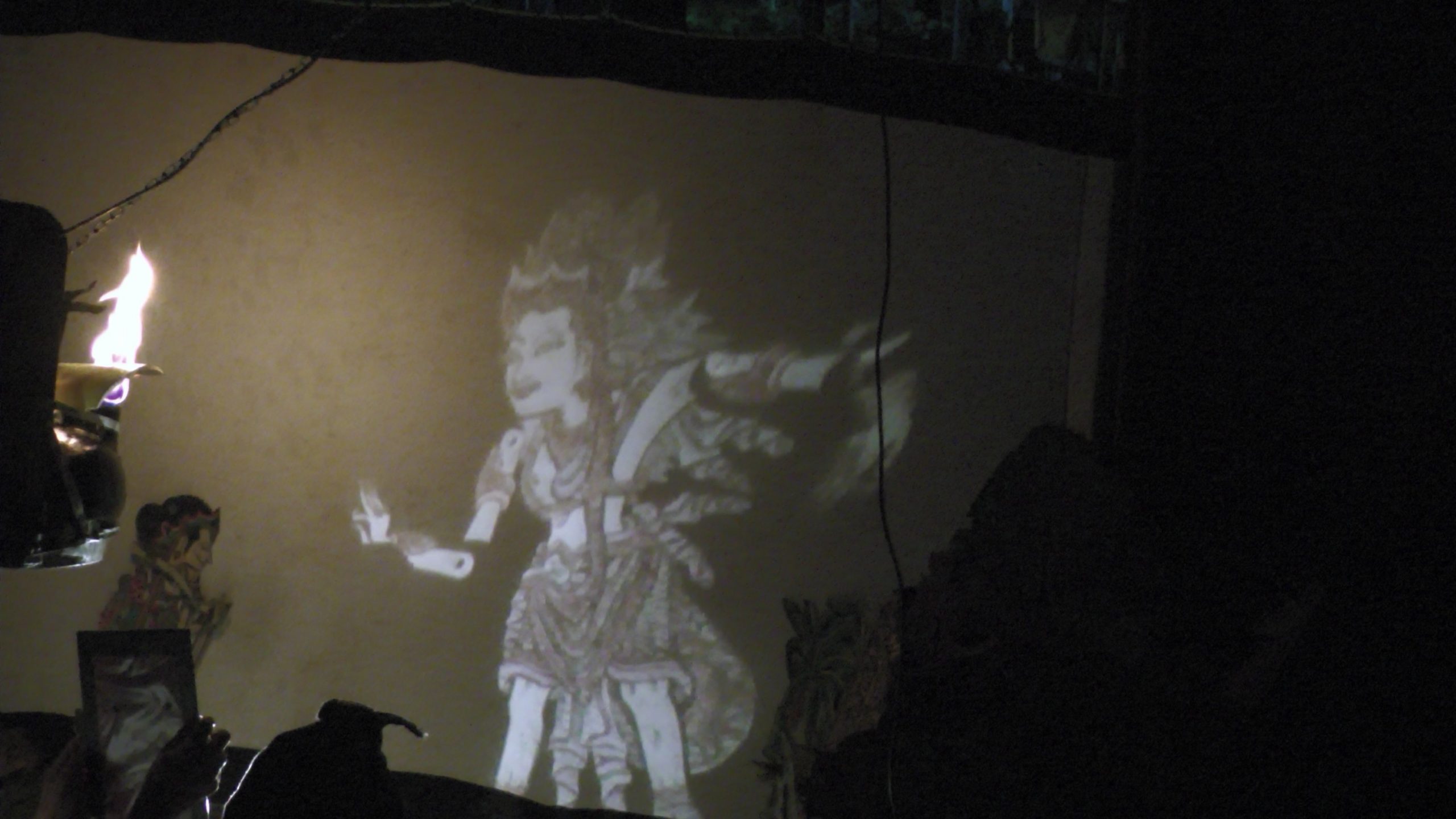 A puppet's figure is projected onto the screen using light and mirrors.