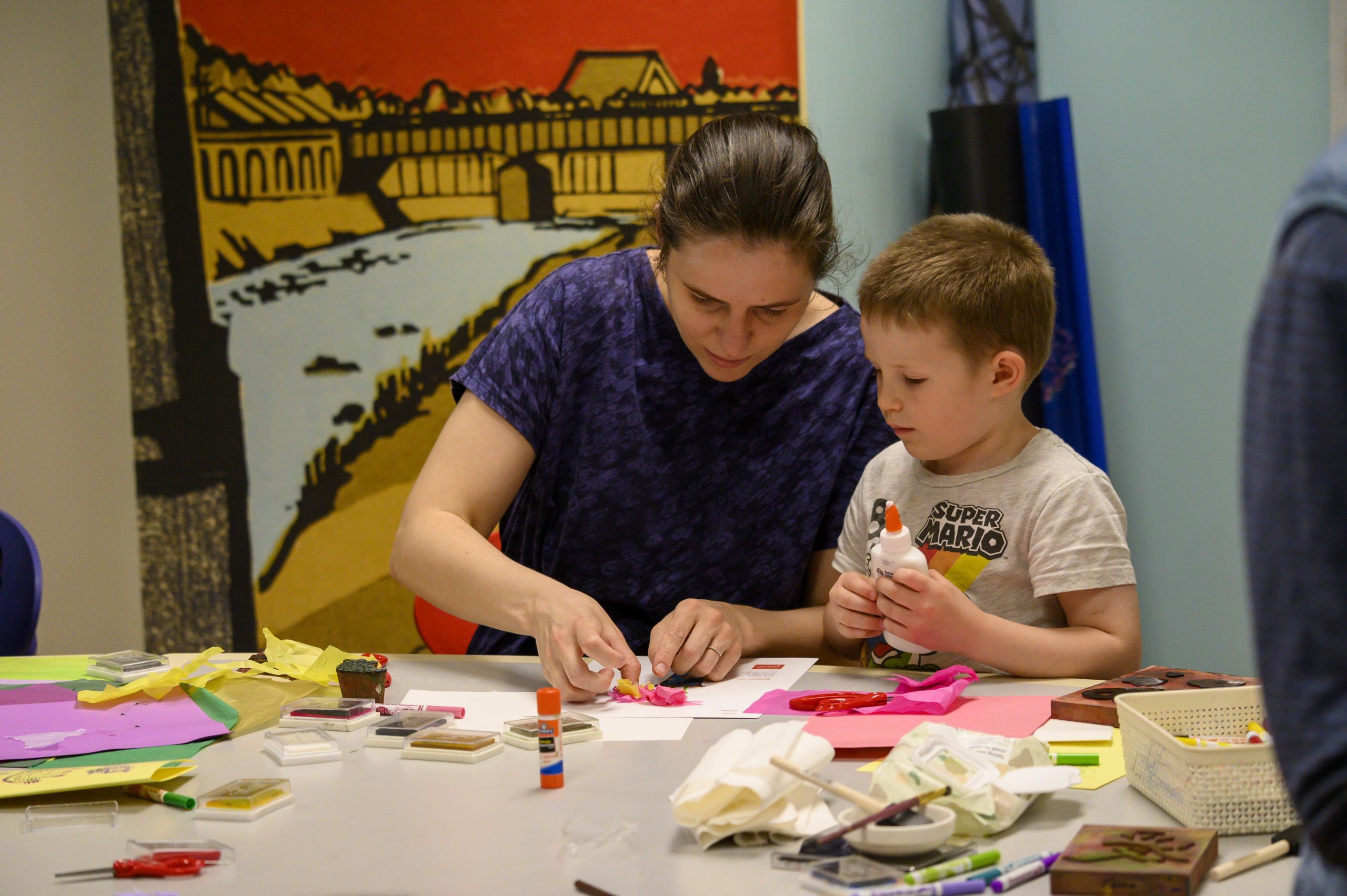 An adult and child making paper crafts together.