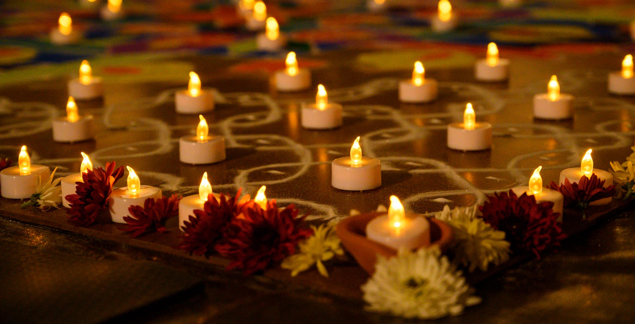 A close-up view of flowers and small votive candles arranged in a geometric pattern.