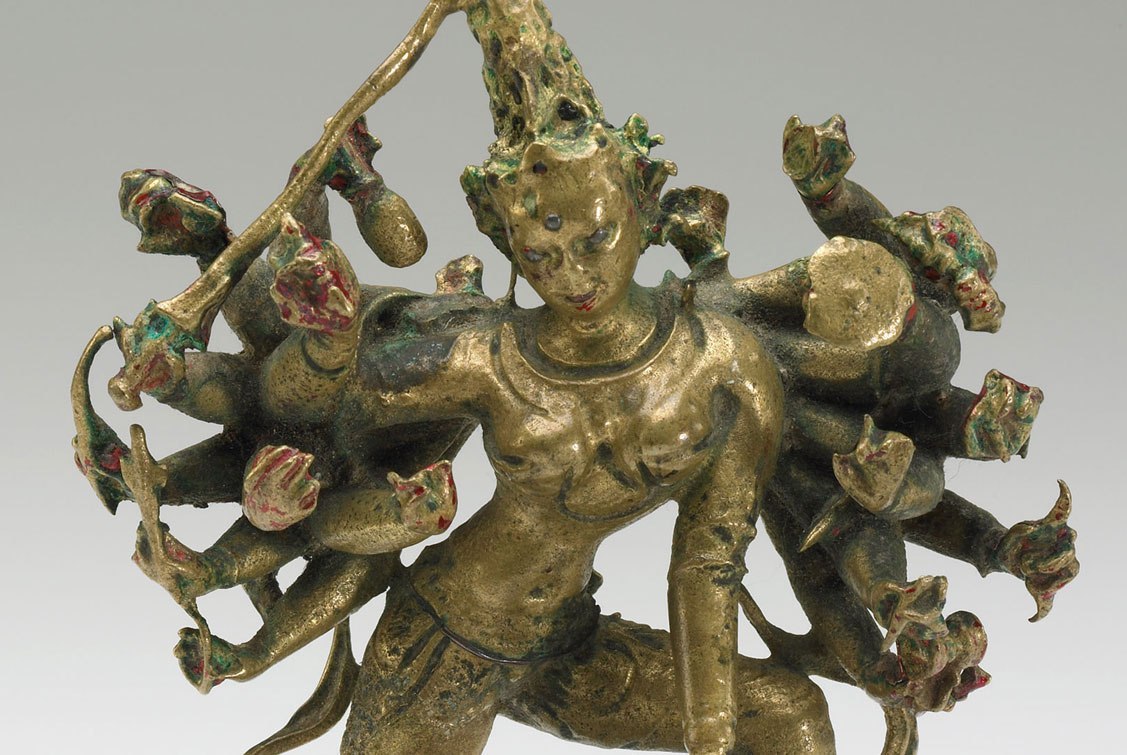 Brass sculpture of Durga, shown in her eighteen-armed form, holds symbols of power and divinity, including a bow and arrow, a sword, a shield, and a drum.