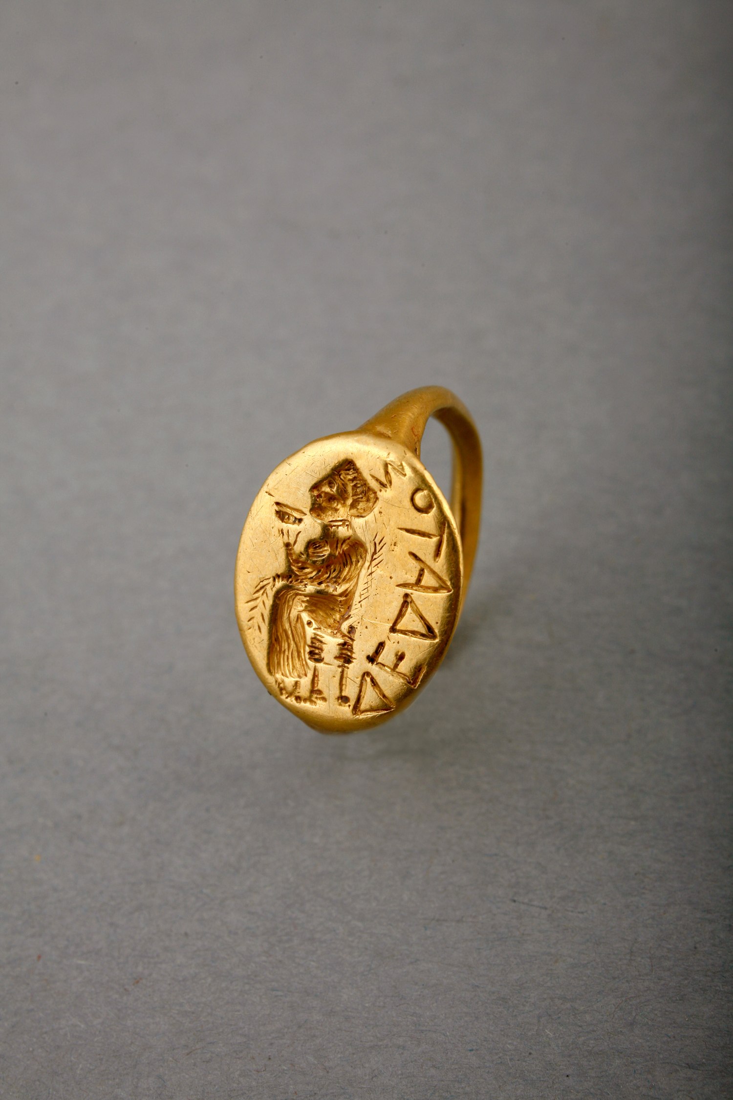 finger ring featuring a seated woman drinking from a wine cup (phiale).