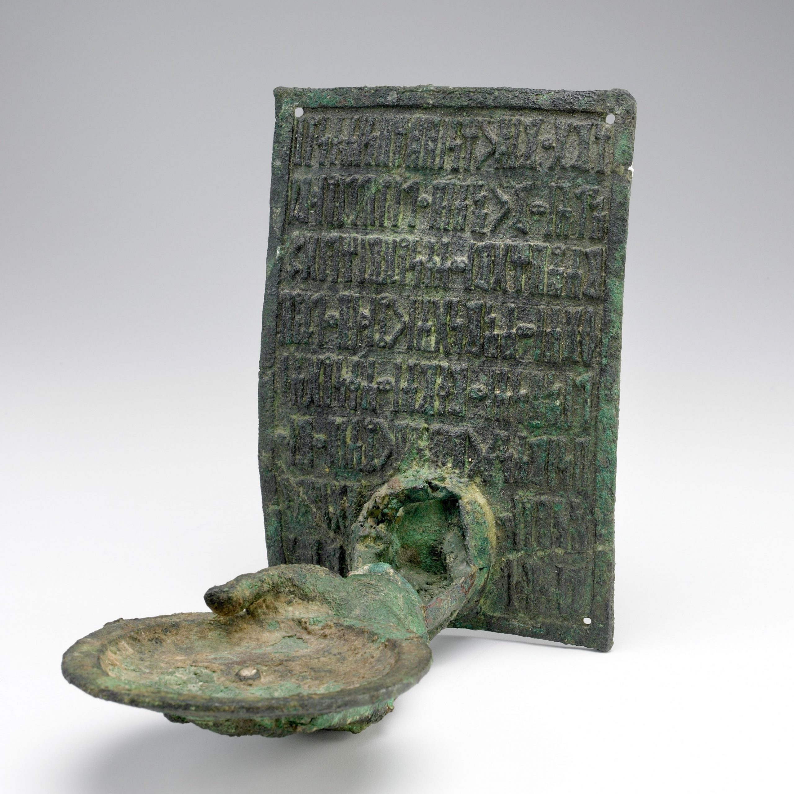 Bronze inscribed plaque with lamp extended by hand