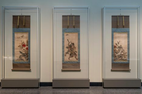 Three Japanese hanging scrolls, each displayed in its own protective glass case.