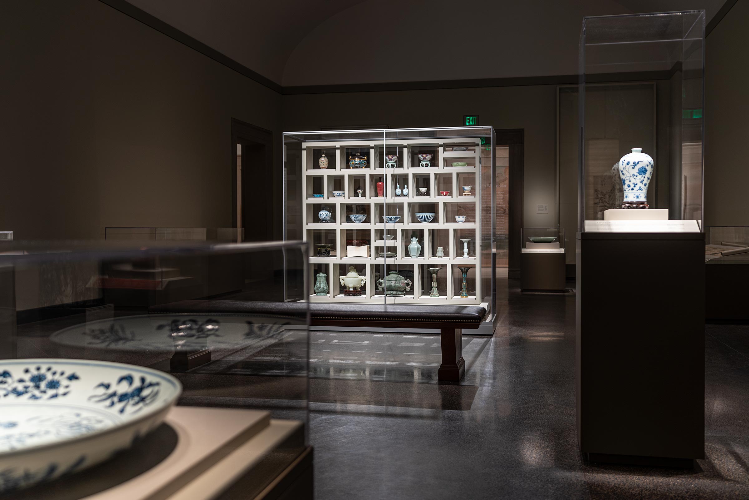 A square white shelf of different sized squares holds ceramics of various sizes and shapes.