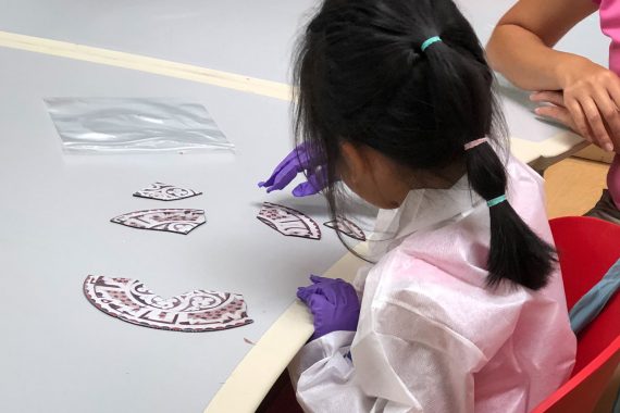 A child putting together a puzzle shaped like a plate in the NMAA collection.