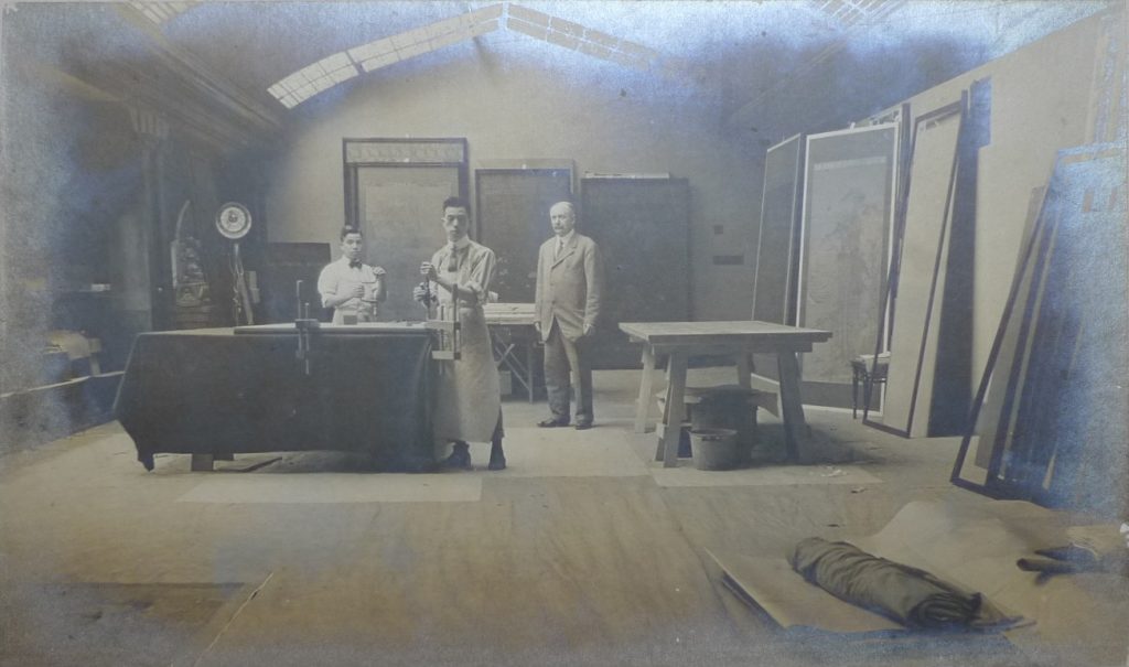 three men in suits standing behind a table in large hall